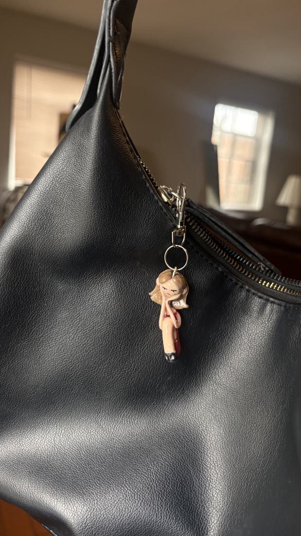 Sitting Mini Mini charm on a black bag